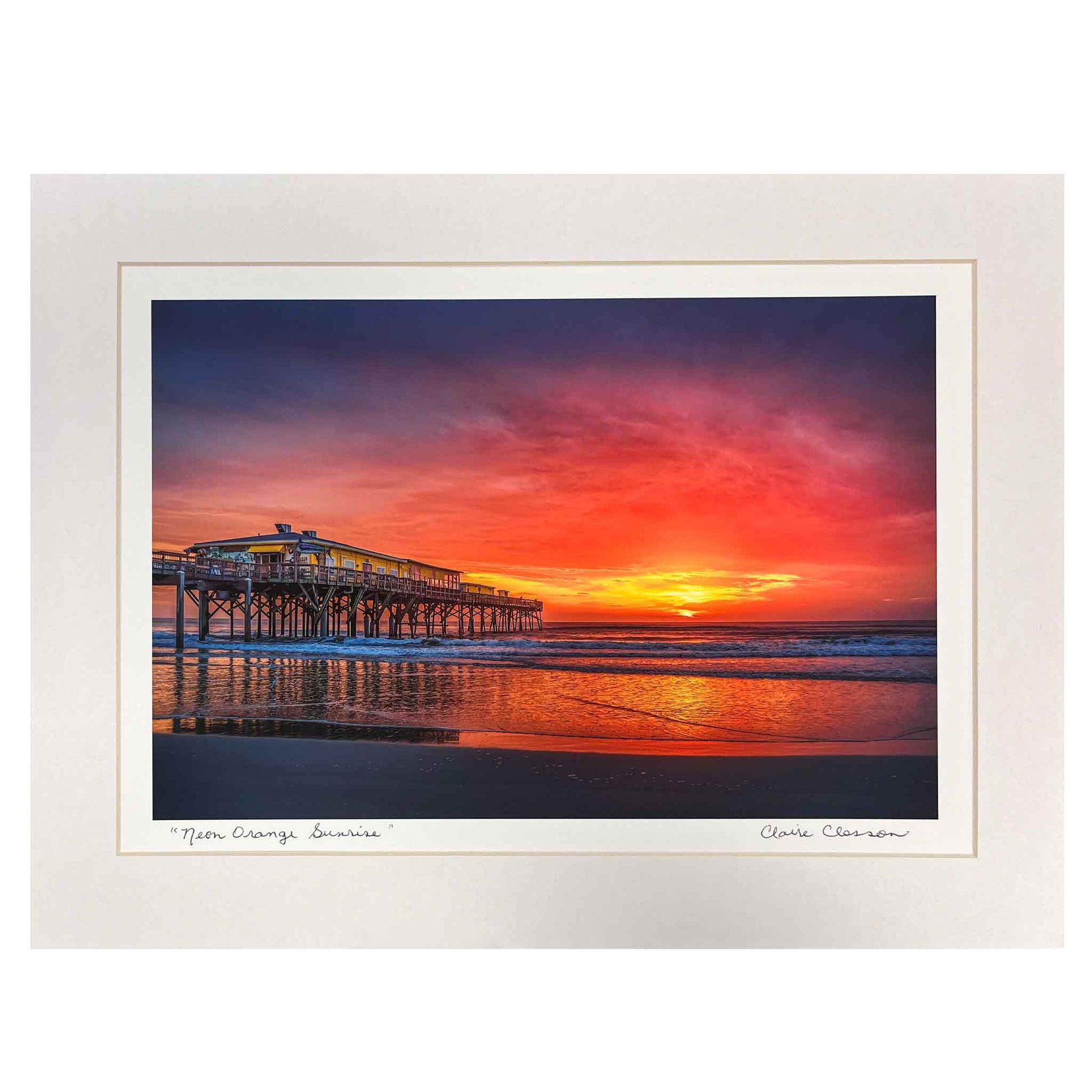 ECC “Neon Orange Sunrise” Matted Print by Photographer Claire Closson. Famed Crabby Joe's Seafood on the Sunglow Pier in Daytona Beach Shores, Florida. Neon orange , brilliant yellows and purple skies are reflected in the ocean. A beautiful photorgaph for any home. 12 x 16 matted and ready to be framed.