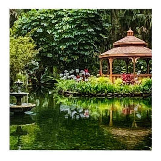 ECC “Summer Daydreams” Framed Print by Photographer Claire Closson.  Stunning photograph of a gazebo on the water surrounded by flowers and lush green.  A tiered fountain cascades water.  Soft reflections in the water.  A 5 x 7 print framed to 8 x 10 inches under glass.  Matted in white with a gray wooden frame.