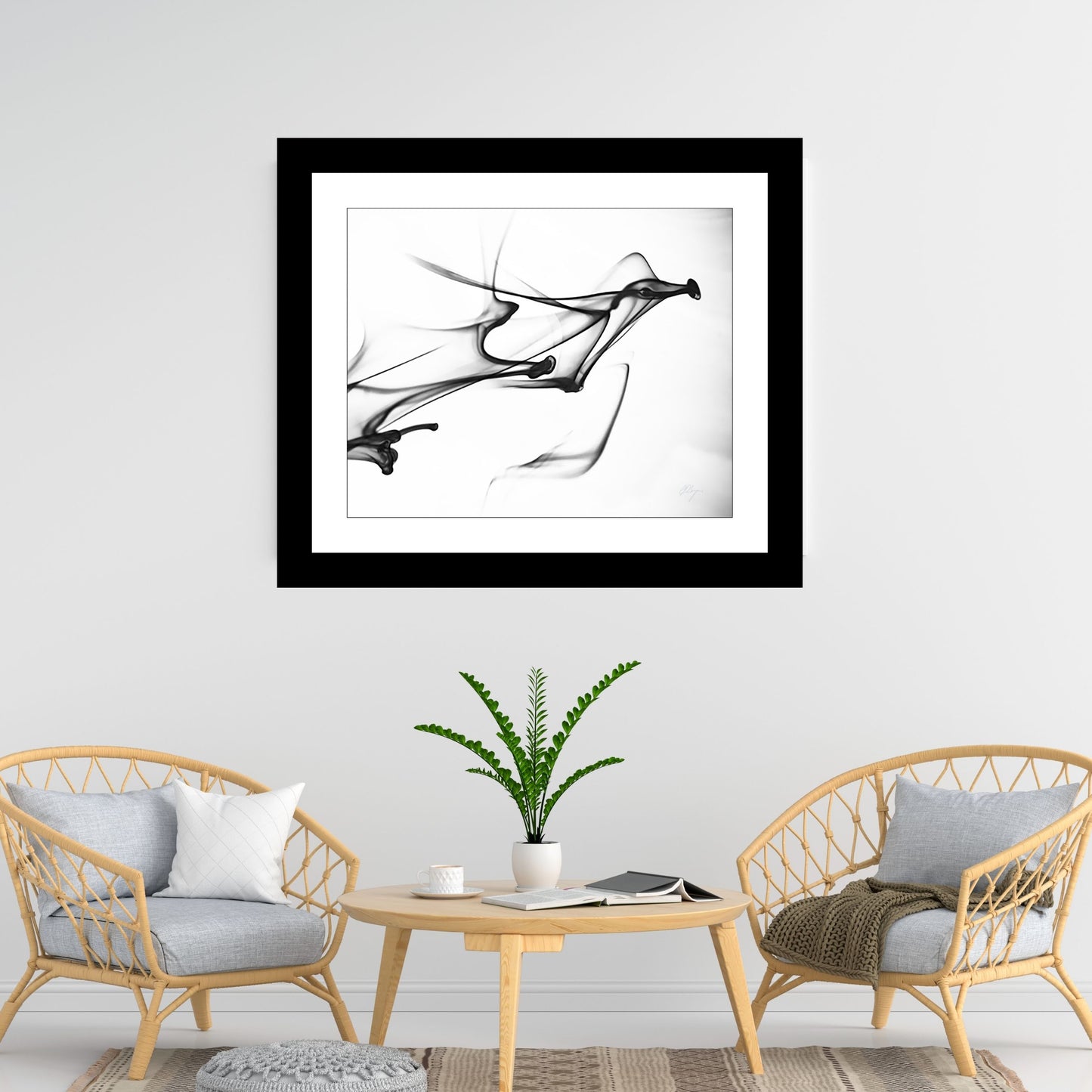 abstract bird in flight photograph with white mat and black frame hung on a white wall with two rattan chairs and light wood table placed beneath