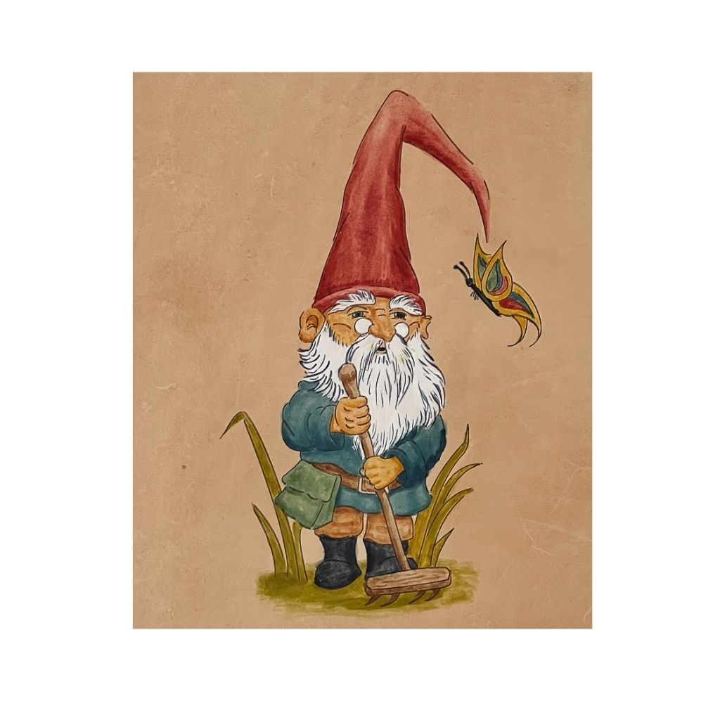 close up of gnome with red hat, blue jacket, holding a garden rake 