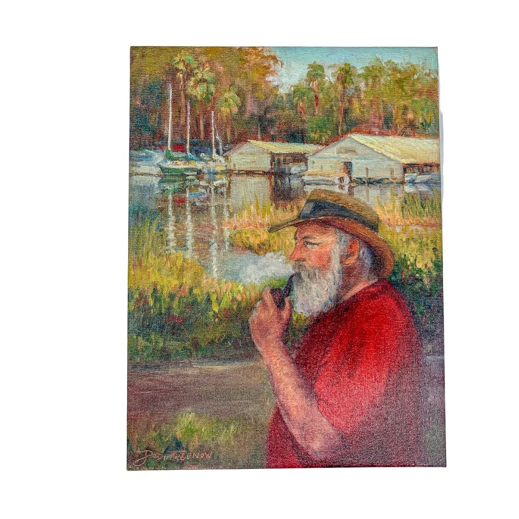 Mt. Dora's Hemingway smoking a pipe, painting on canvas with lake and boat houses in the background