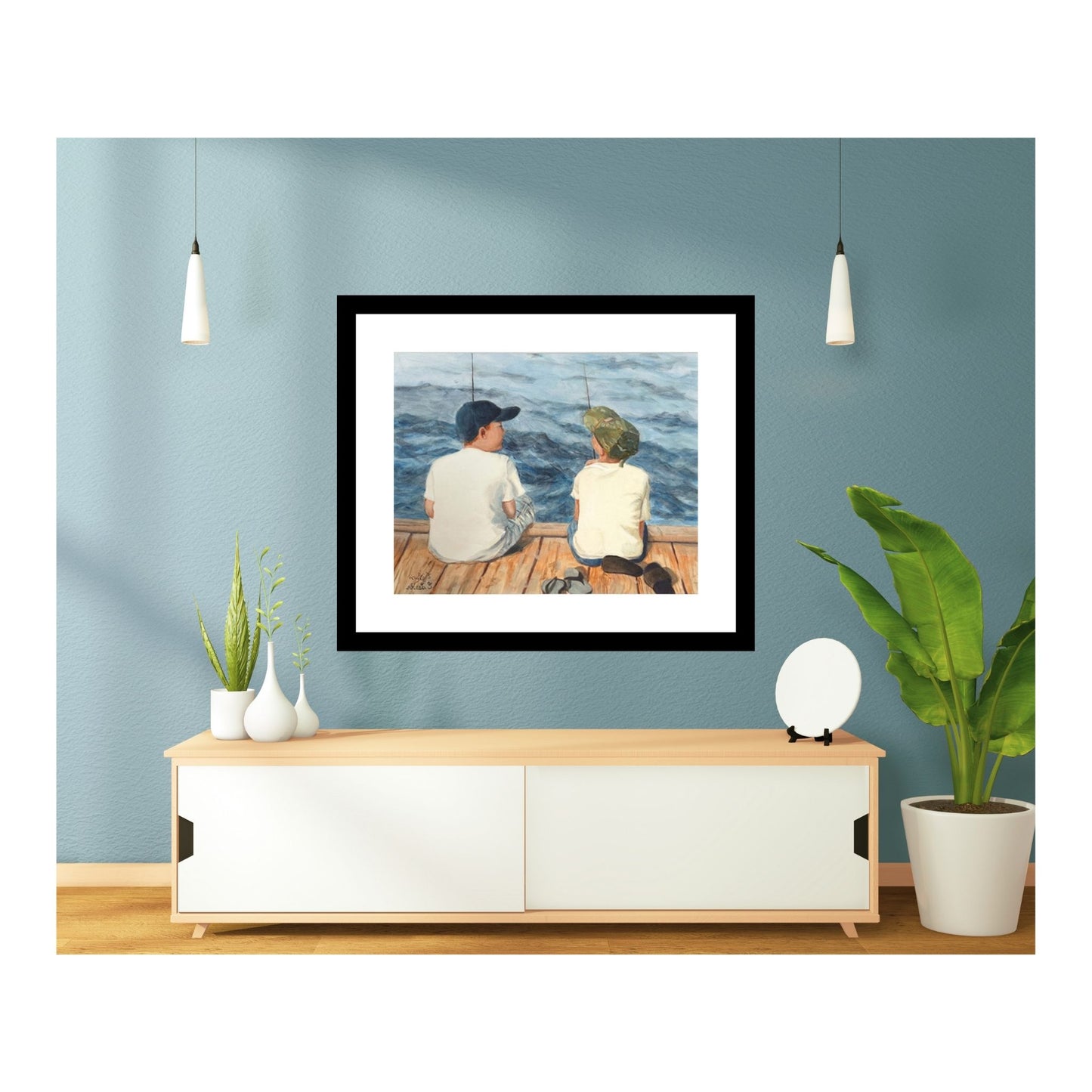 two boys fishing print with a black frame above a white credenza on a blue wall
